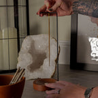 Person holding a incense stick near holder bowl with a crystal formation in the background