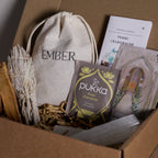 Box containing Ember and Pukka tea, palo santo and sage on a wooden surface