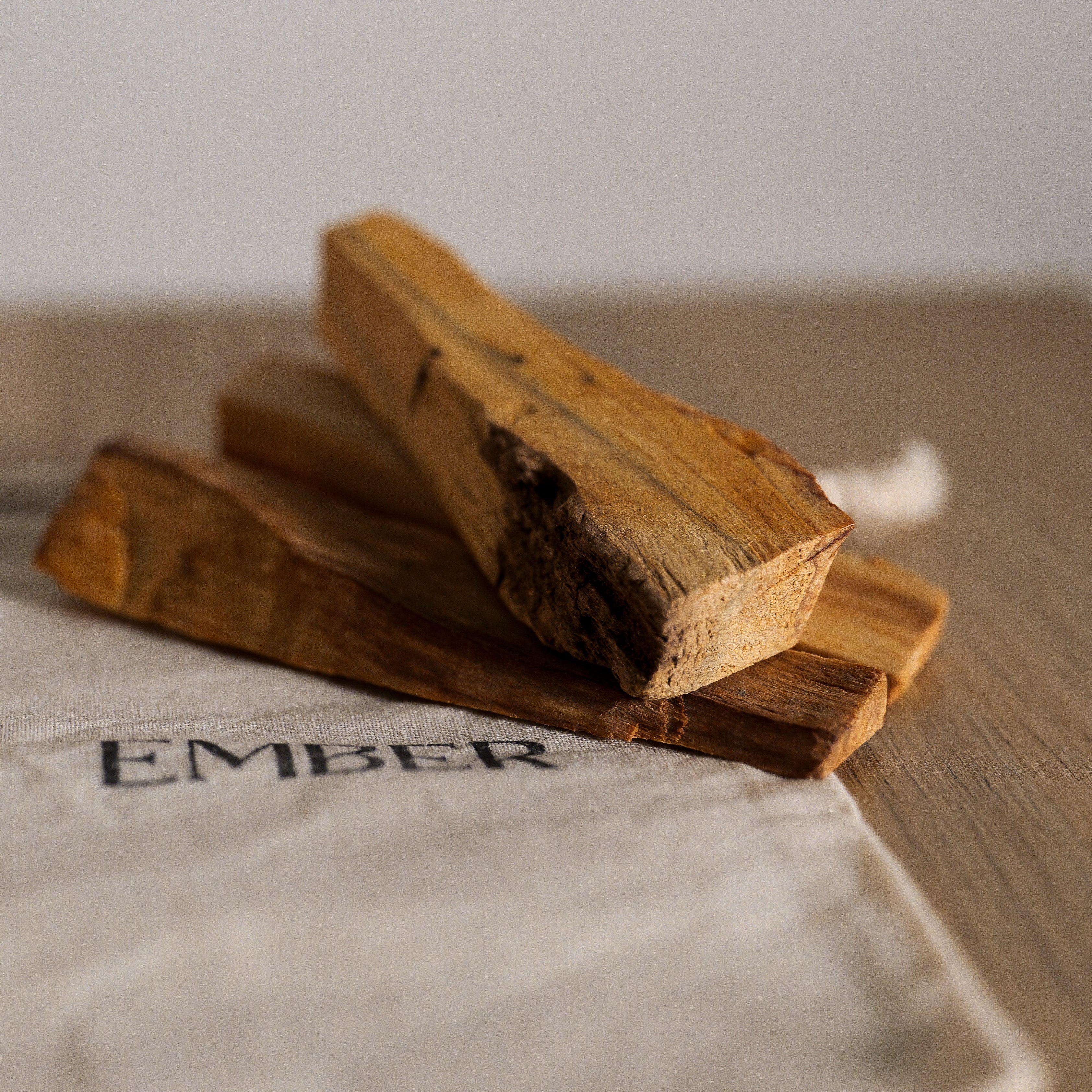 Three pieces of palo santo products on a white cloth with a blurred background