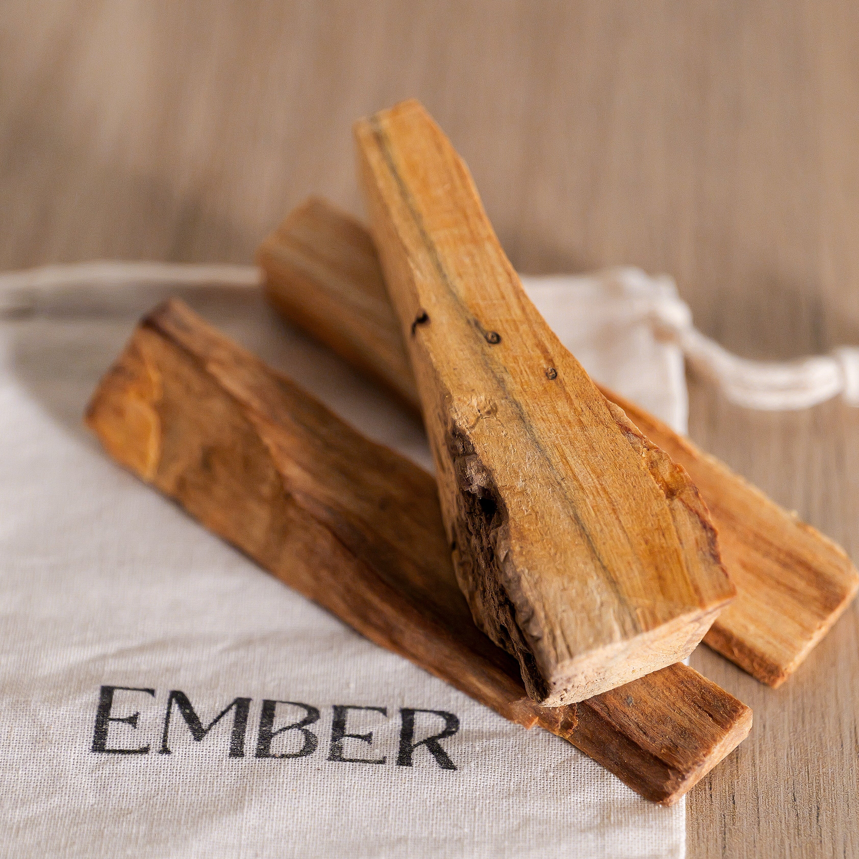 Two wooden logs on a white cloth with 'EMBER' branding on a wooden surface.