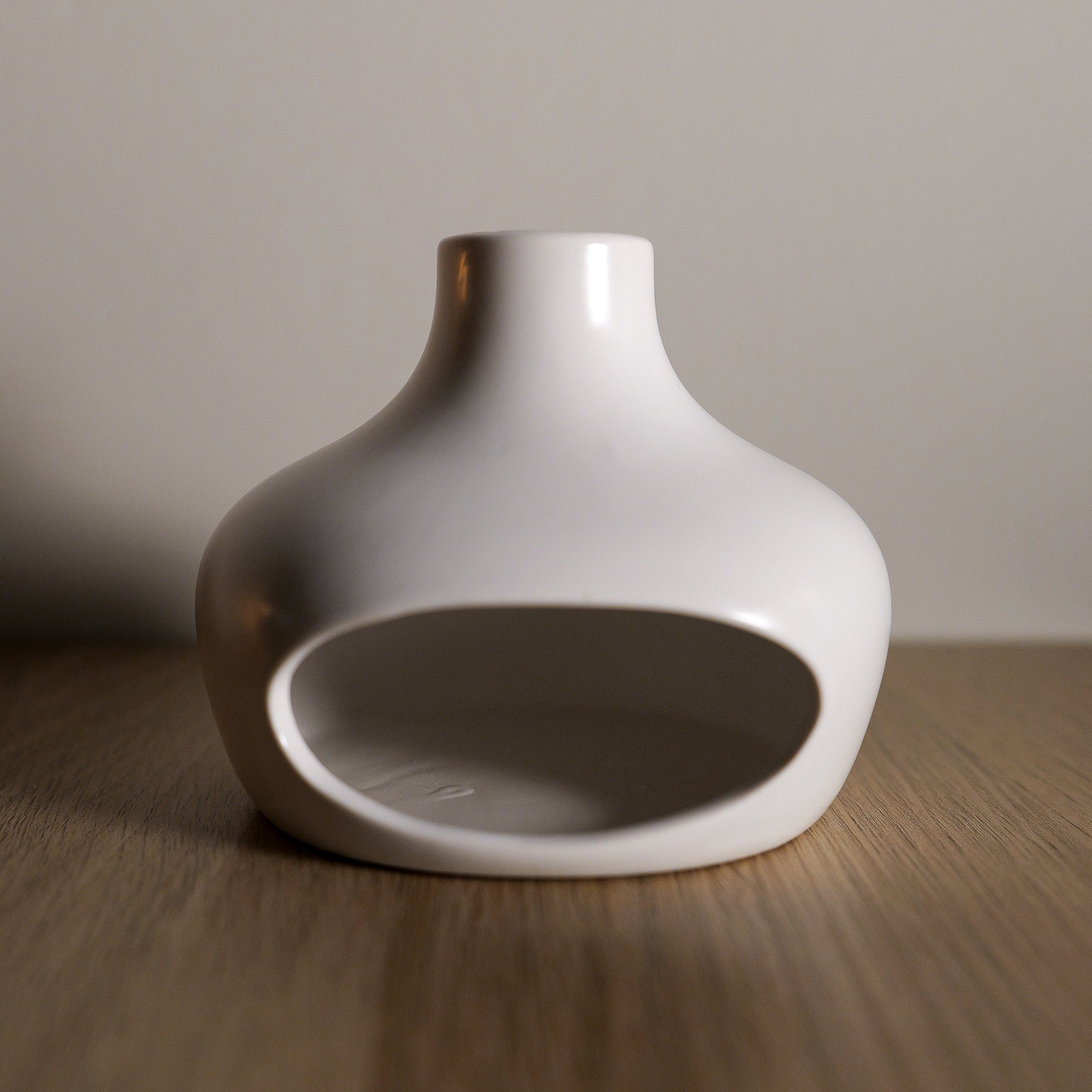 White ceramic Palo santo holder on a wooden surface with a neutral background